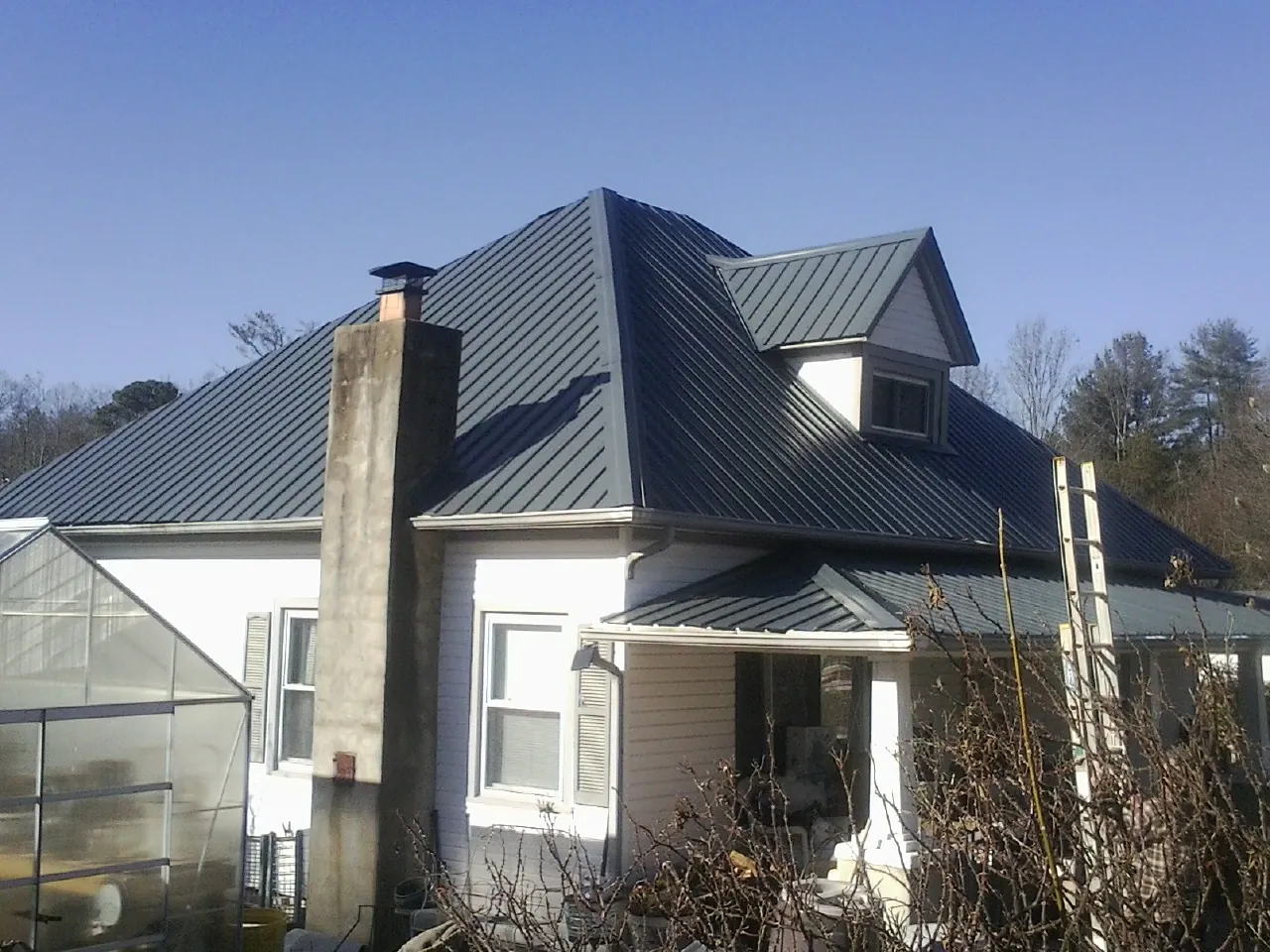 Dark blue standing seam metal roof on a white farmhouse with dormer — Slate & Tile Roof Repair by Roofing Brothers in Laguna