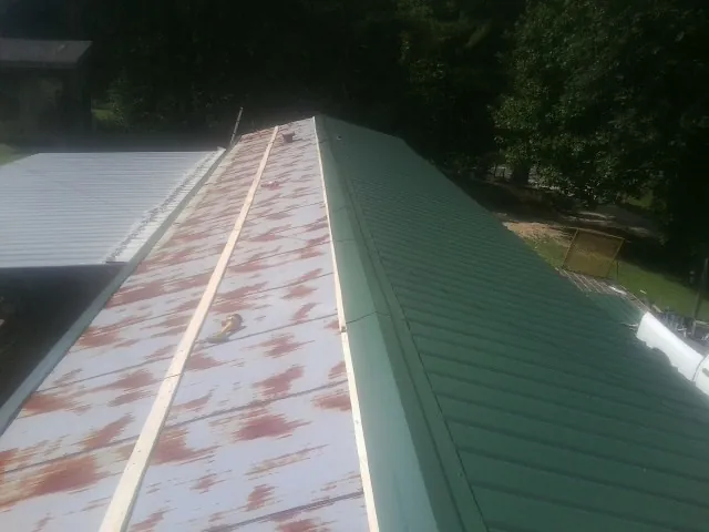 Old rusted panels beside newly installed green metal roofing — Wind Damage Roof Repair by Roofing Brothers in Laguna