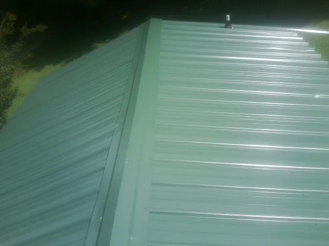 New green metal panels meeting at the ridge of a roof — Flat Roof Repair work by our crew in Laguna