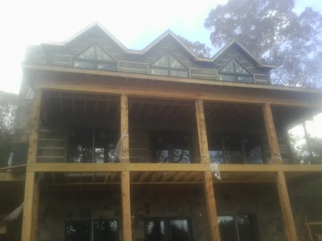 Dormers and porch framing on a large log home under construction — Roof Coating work by our crew in Laguna