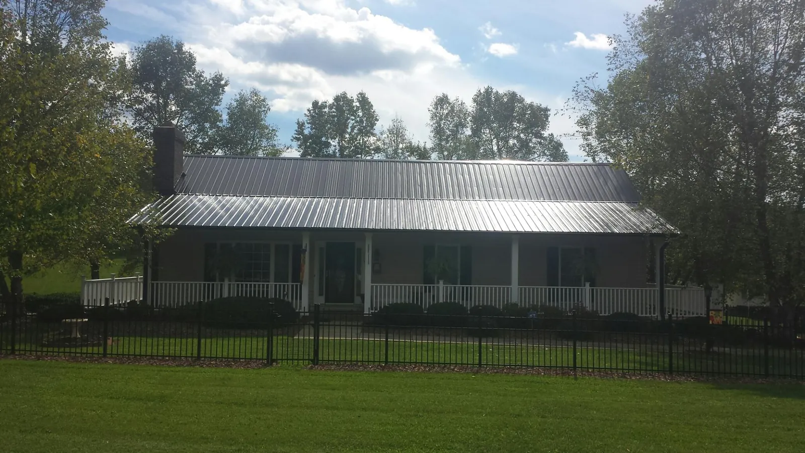 Gray metal roof on a brick ranch with a full width front porch — Gutter Guard Installation work by our crew in Laguna