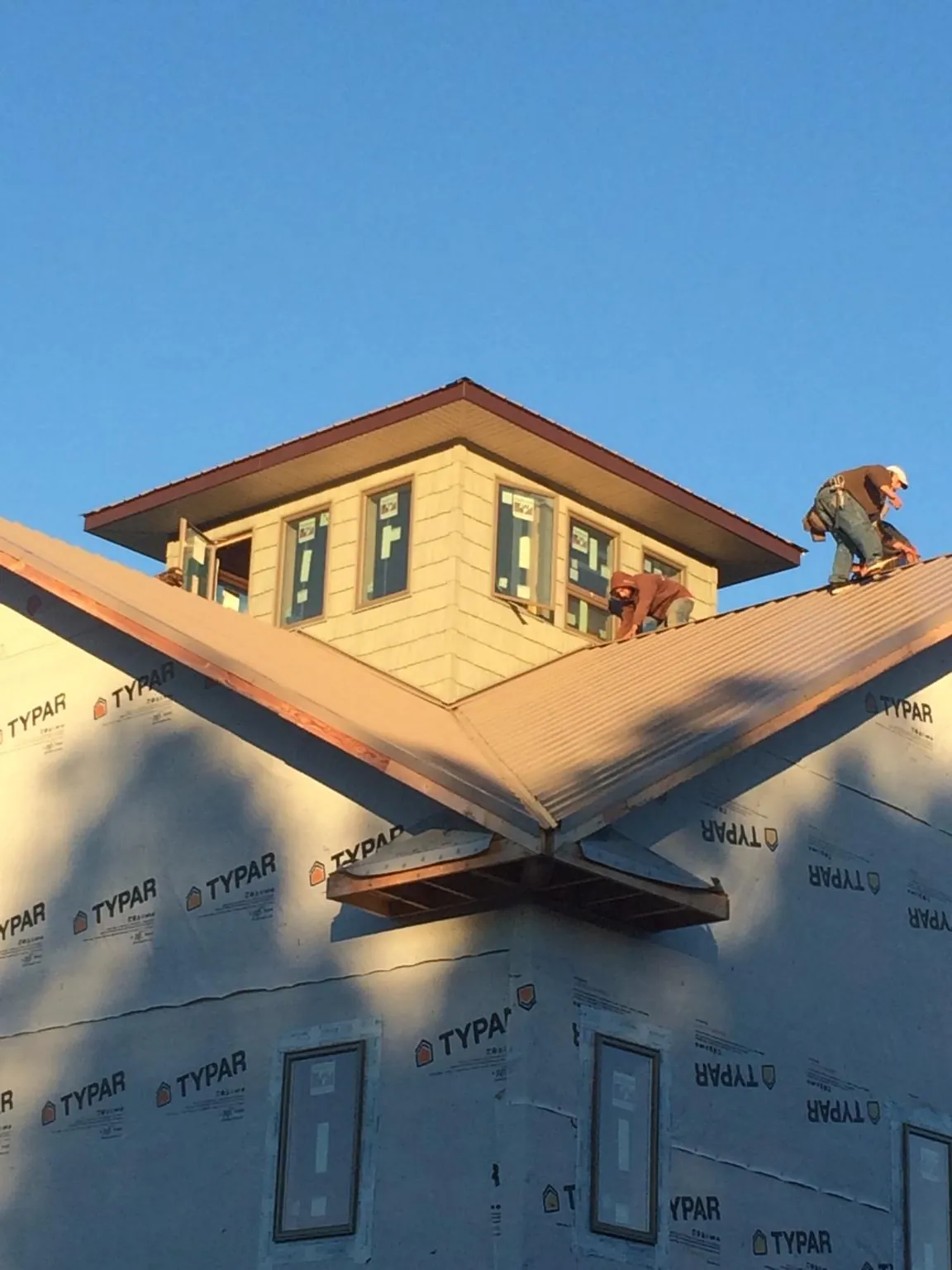 Roofers working around a rooftop cupola on a new metal roof at sunset — Roof Waterproofing in Laguna by Roofing Brothers